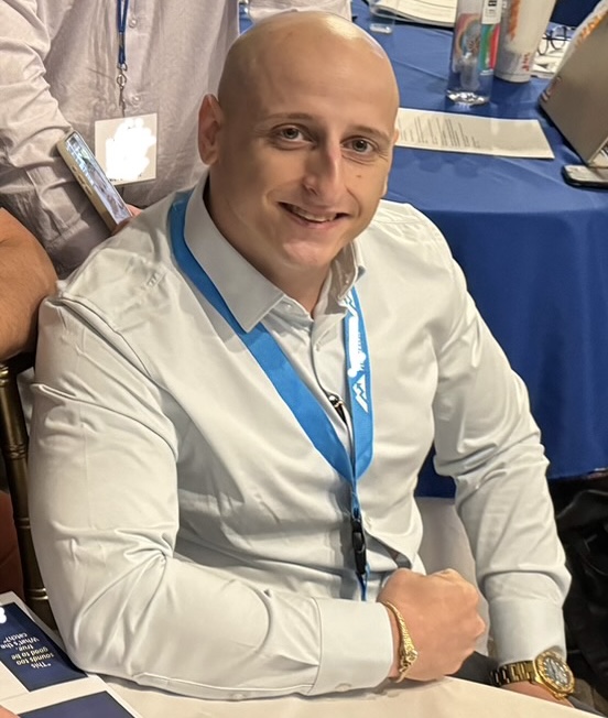 Johnny Al-Jazrawi, smiling, seated at an insurance industry event